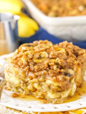 A square serving of Overnight Baked Banana French Toast Casserole next to a silver fork on a white plate