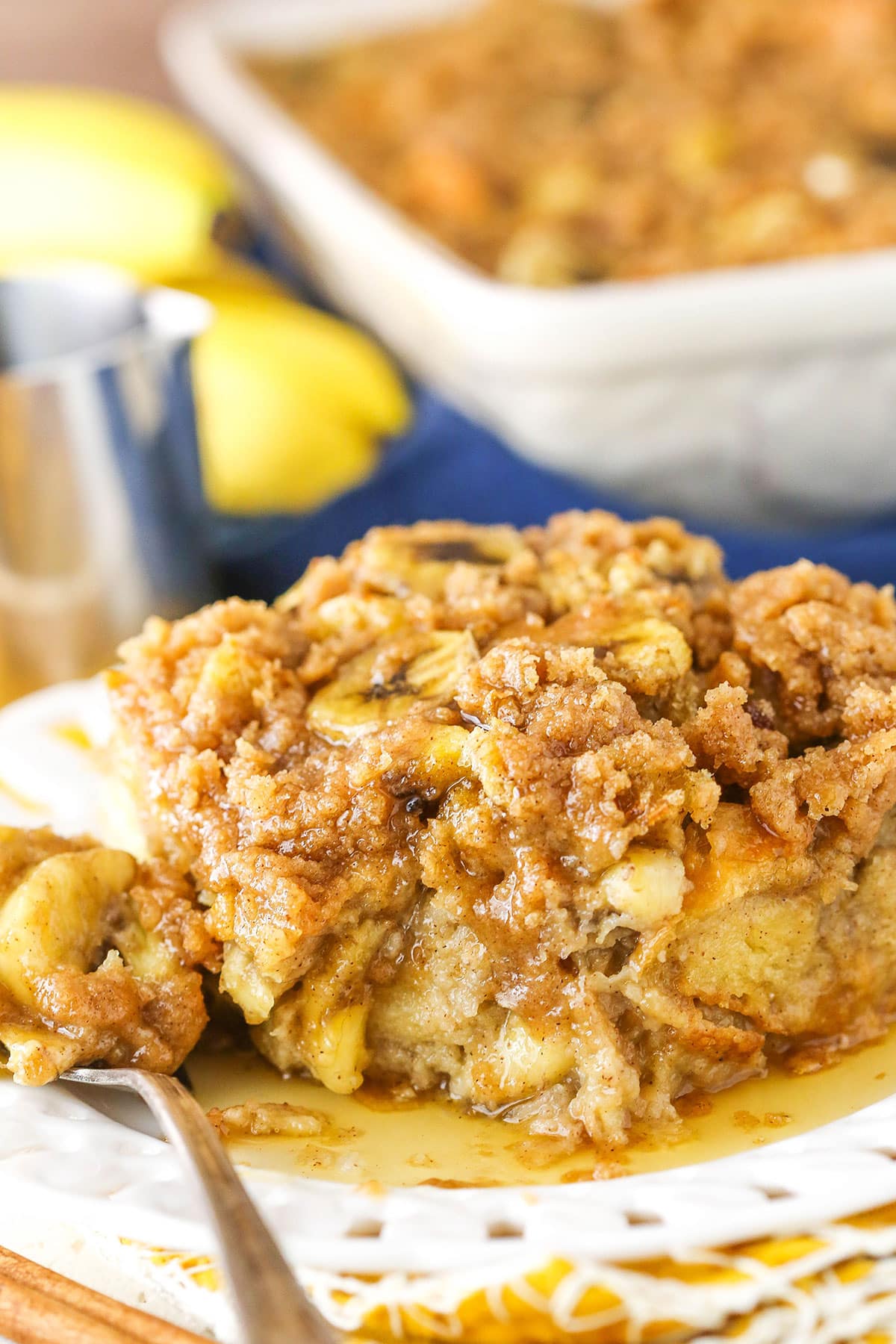 A serving of Overnight Baked Banana French Toast Casserole with a bite removed on a white plate