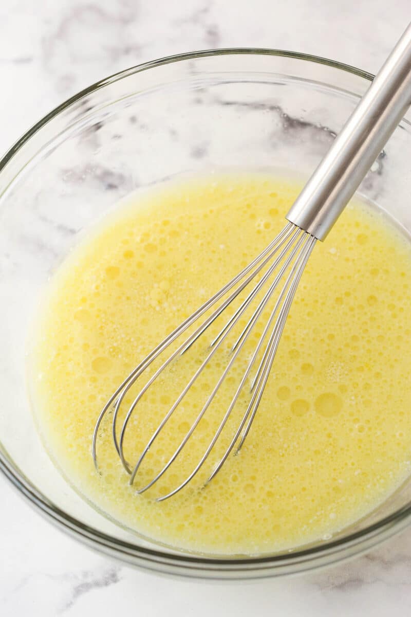 This peanut butter chocolate cake is made with layers of moist chocolate cake, peanut butter frosting and chopped Reese’s peanut butter cups. Whisking together wet ingredients for chocolate cake.