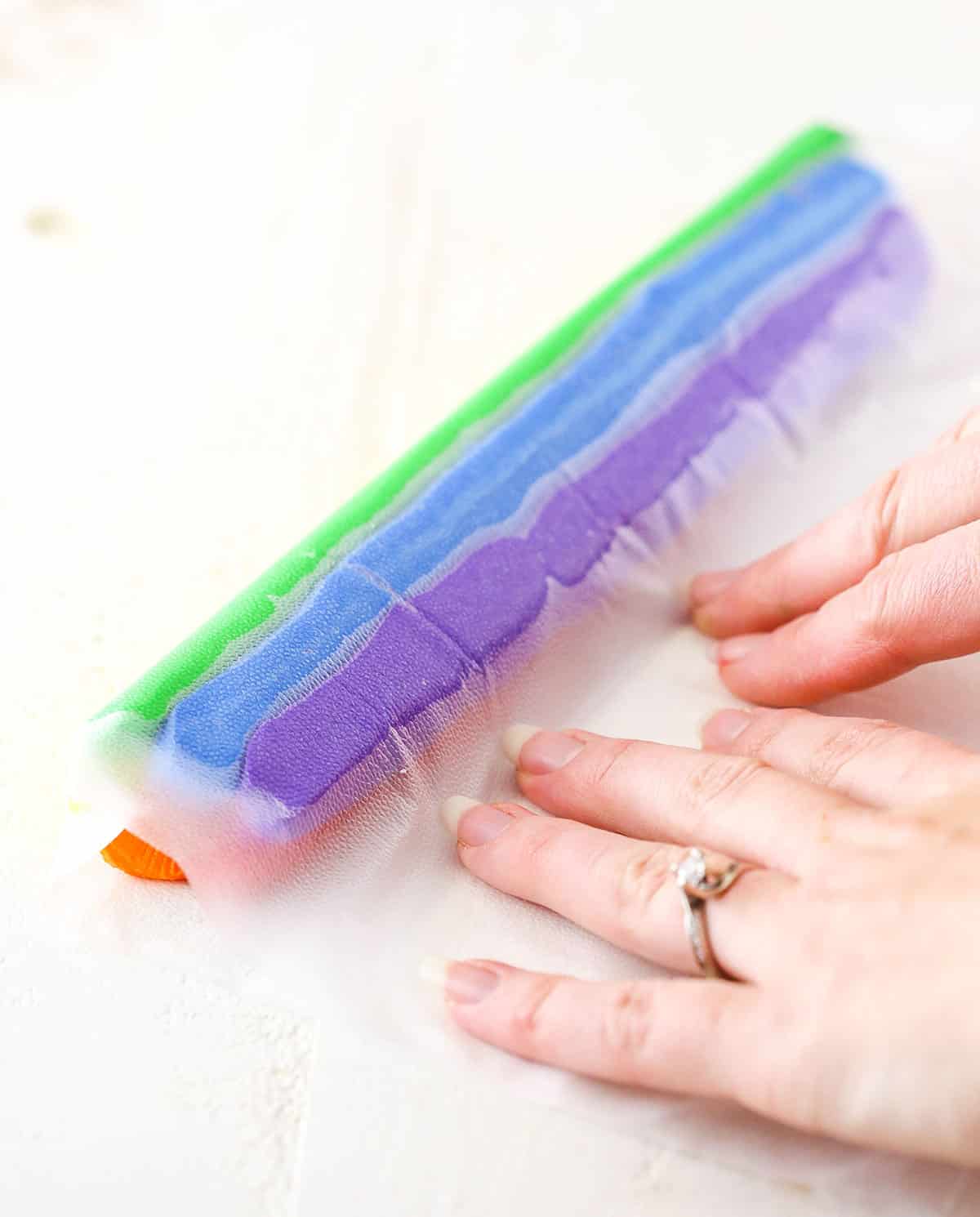 A step in making Rainbow Swirl Cake showing preparing multiple colors of frosting for the piping bag