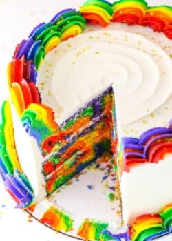 A Rainbow Swirl Cake with a slice removed showing the colorful internal layers