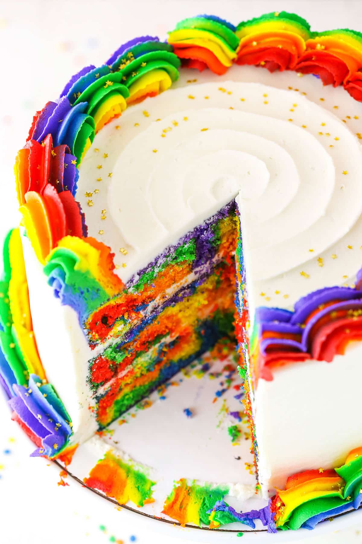 A Rainbow Swirl Cake with a slice removed showing the colorful internal layers