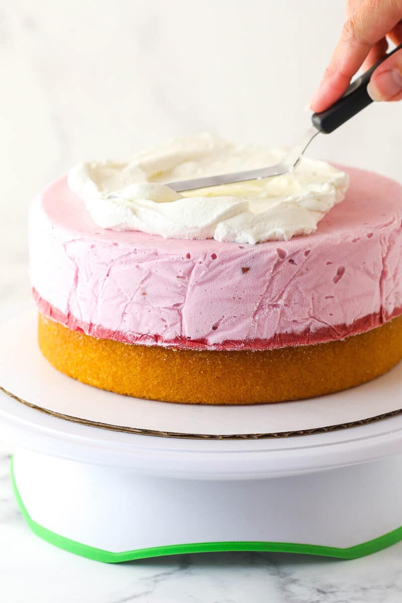 Frosting strawberry ice cream cake with whipped cream.