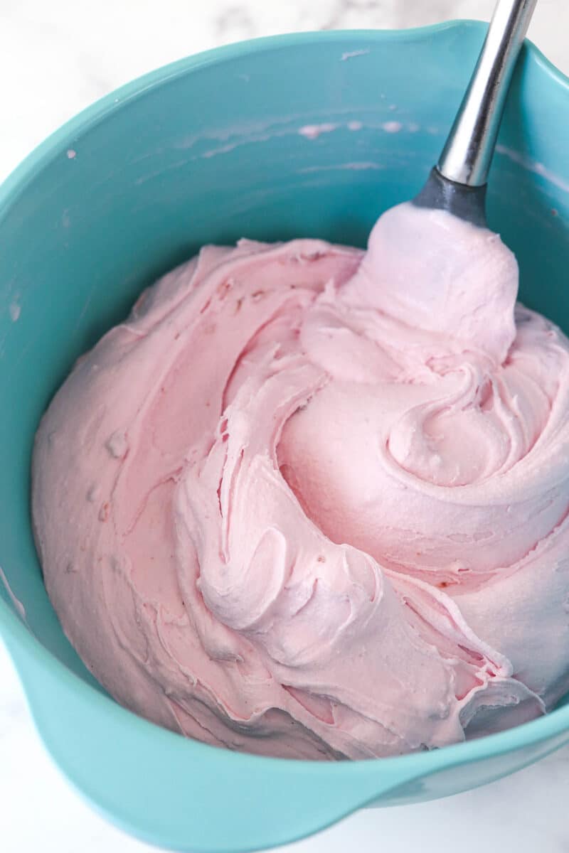 Stirring softened strawberry ice cream until it's nice and creamy and spreadable.