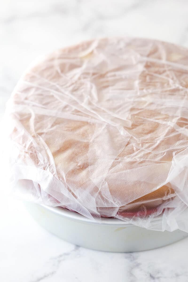 Wrapping clear wrap over ice cream cake in a cake pan.