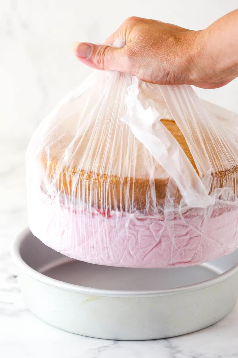 Using clear wrap to remove ice cream cake from a cake pan.
