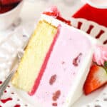 A slice of strawberry ice cream cake on a plate with a fork.