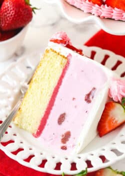 A slice of strawberry ice cream cake on a plate with a fork.