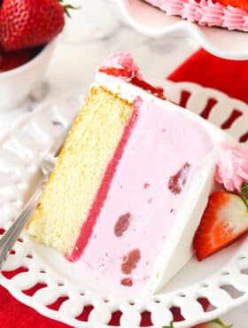 A slice of strawberry ice cream cake on a plate with a fork.
