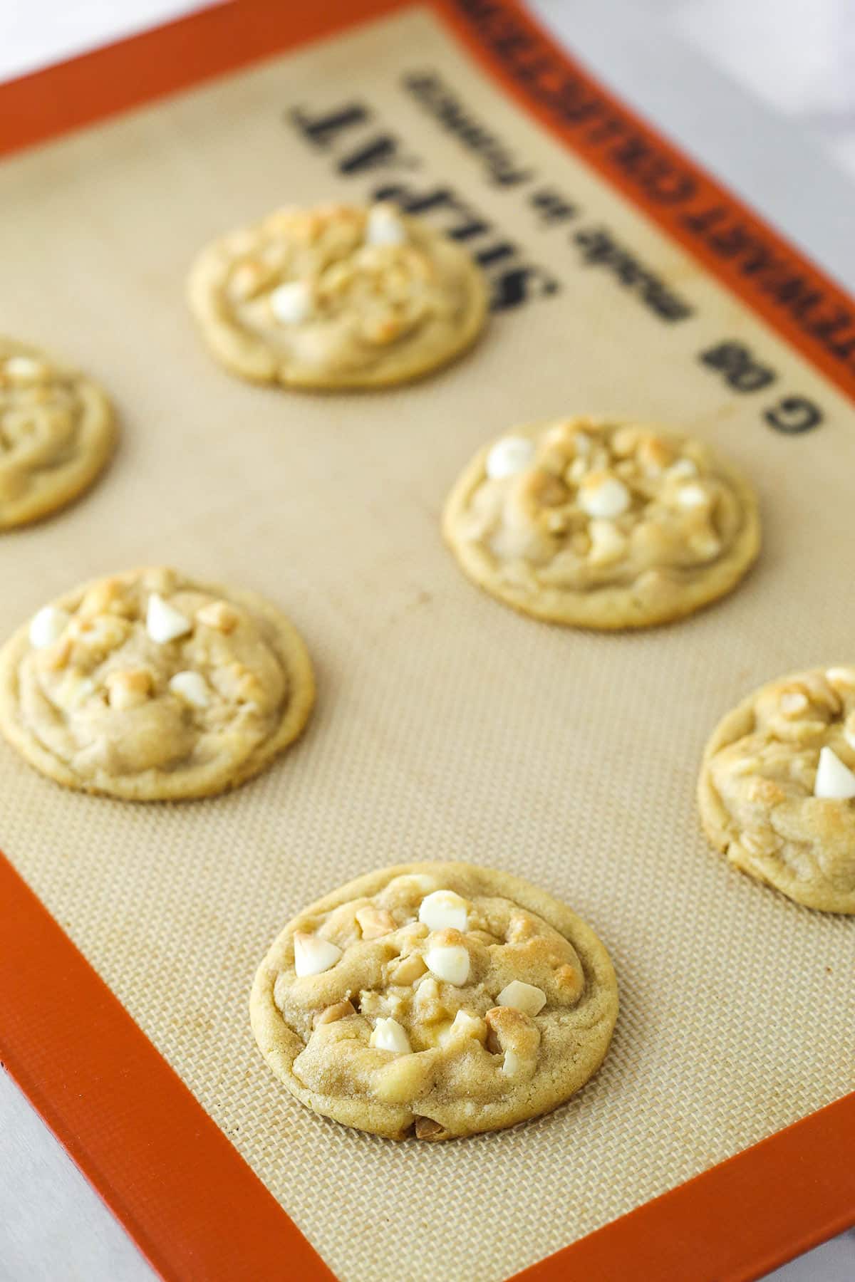 Macadamia nut cookies baked on a silicone mat.