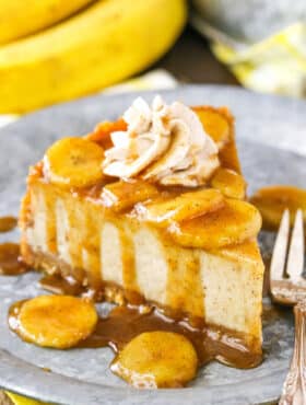 A slice of Bananas Foster Cheesecake next to a silver fork on a gray plate