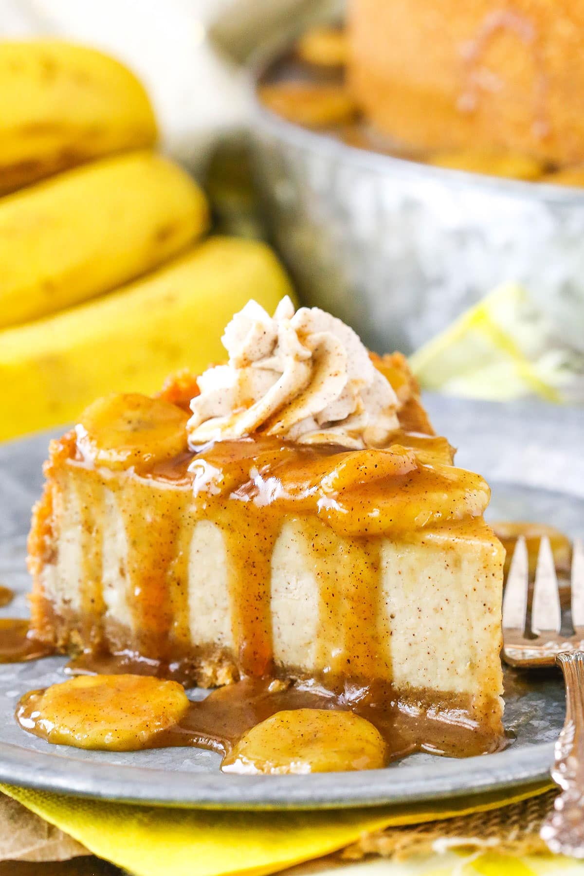 A slice of Bananas Foster Cheesecake next to a silver fork on a gray plate