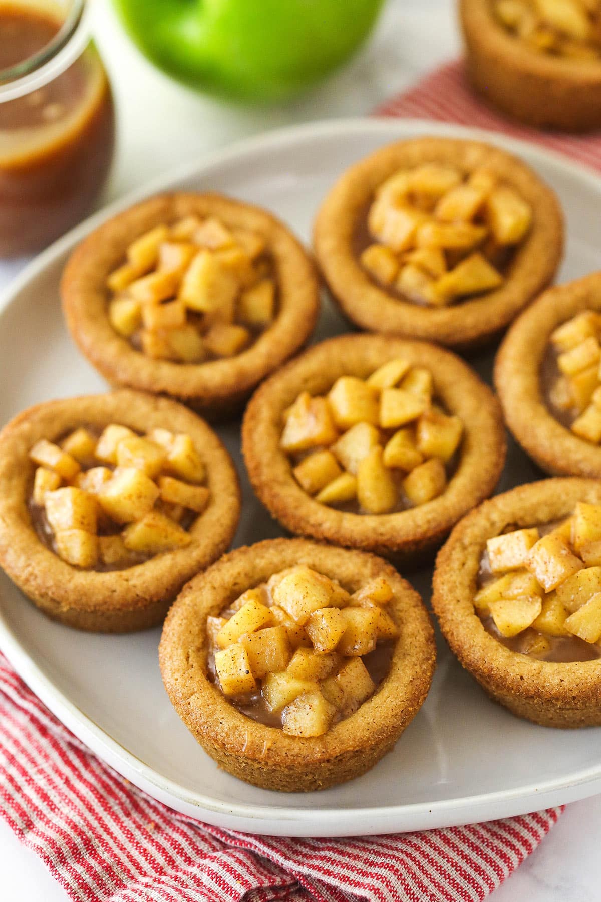 caramel apple cookie cups on beige plate on red and white striped napkin