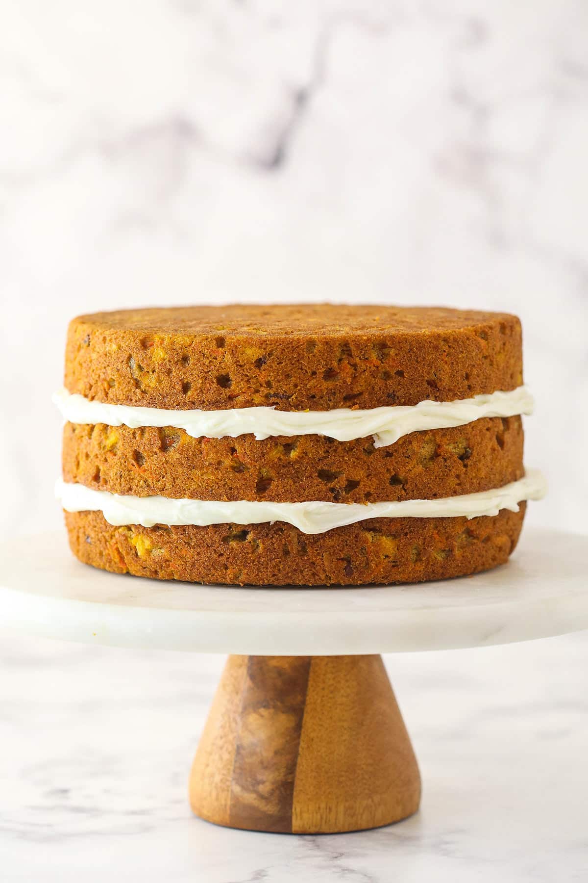 Stacking and filling carrot cake layers with cream cheese frosting.