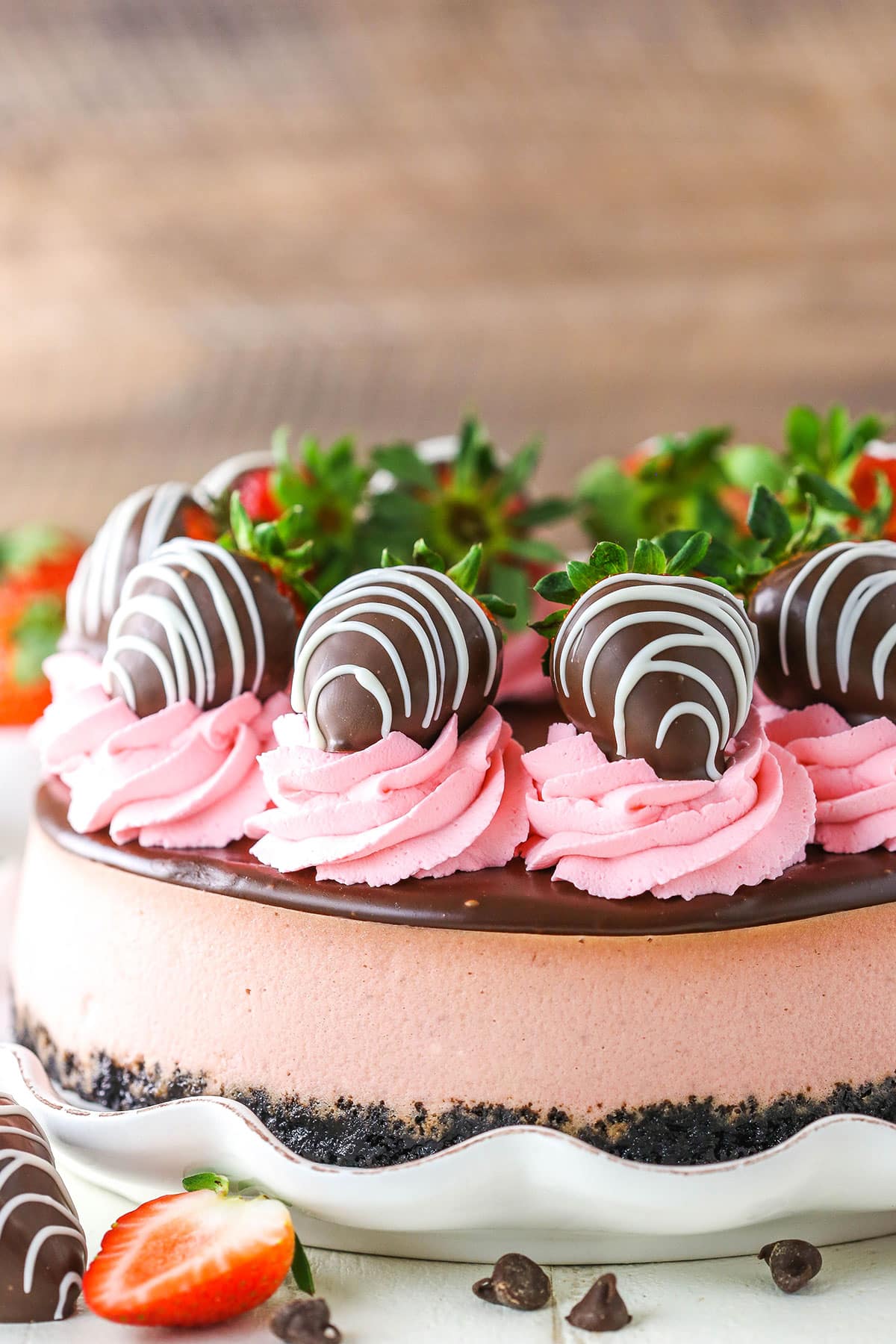 Side view of a full Chocolate Covered Strawberry Cheesecake on a white cake stand