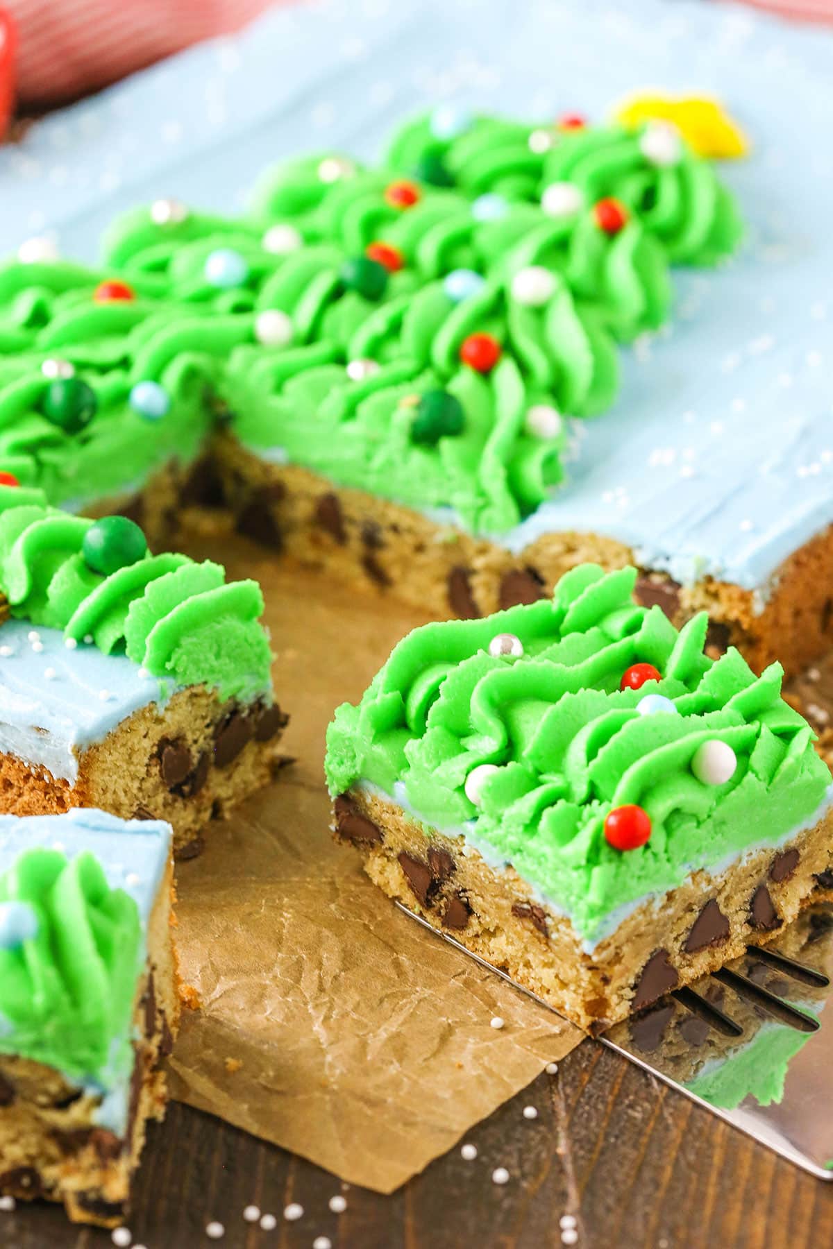 A square slice of Christmas Tree Chocolate Chip Cookie Cake being removed from the whole cake