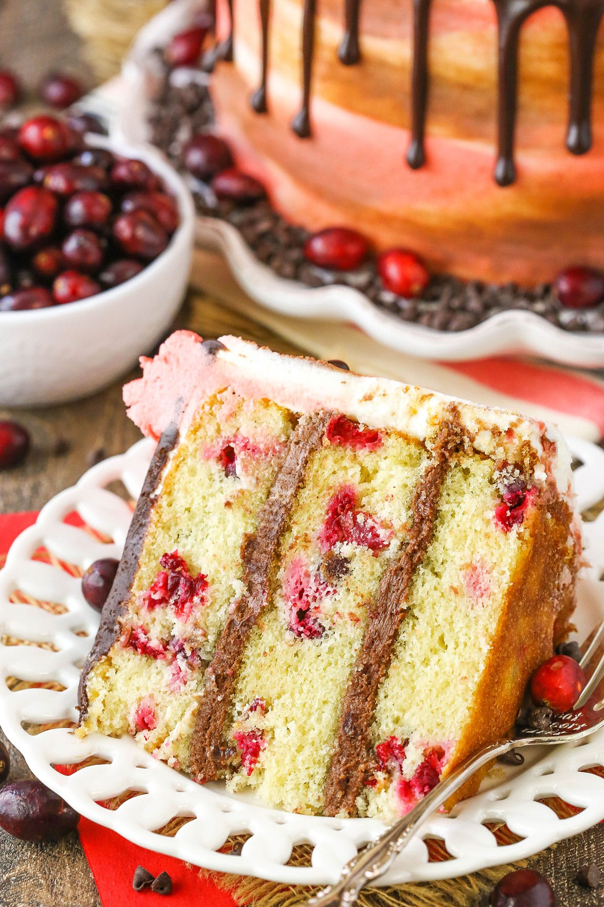 A slice of Cranberry Fudge Layer Cake next to a fork on a white plate