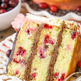 A slice of Cranberry Fudge Layer Cake next to a fork on a white plate
