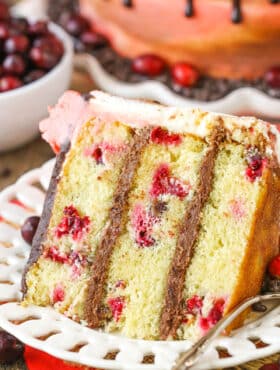 A slice of Cranberry Fudge Layer Cake next to a fork on a white plate