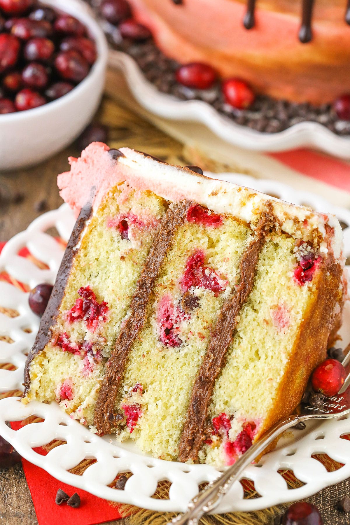 A slice of Cranberry Fudge Layer Cake next to a fork on a white plate