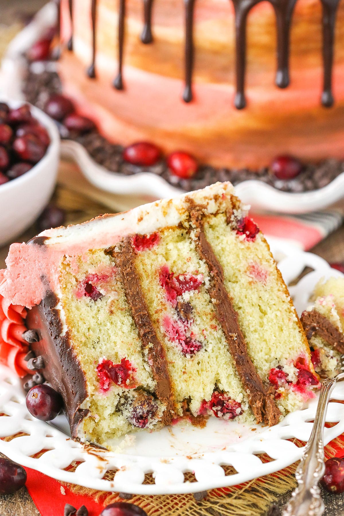 A slice of Cranberry Fudge Layer Cake with a bite removed next to a fork on a white plate