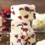 Three White Chocolate Cranberry Fudge cubes stacked on a wooden table