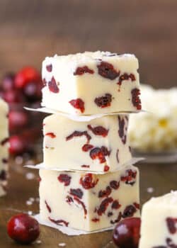 Three White Chocolate Cranberry Fudge cubes stacked on a wooden table