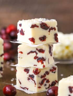 Three White Chocolate Cranberry Fudge cubes stacked on a wooden table