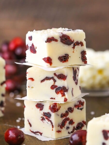 Three White Chocolate Cranberry Fudge cubes stacked on a wooden table