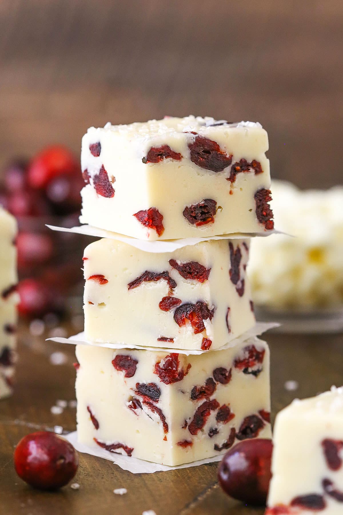Three White Chocolate Cranberry Fudge cubes stacked on a wooden table