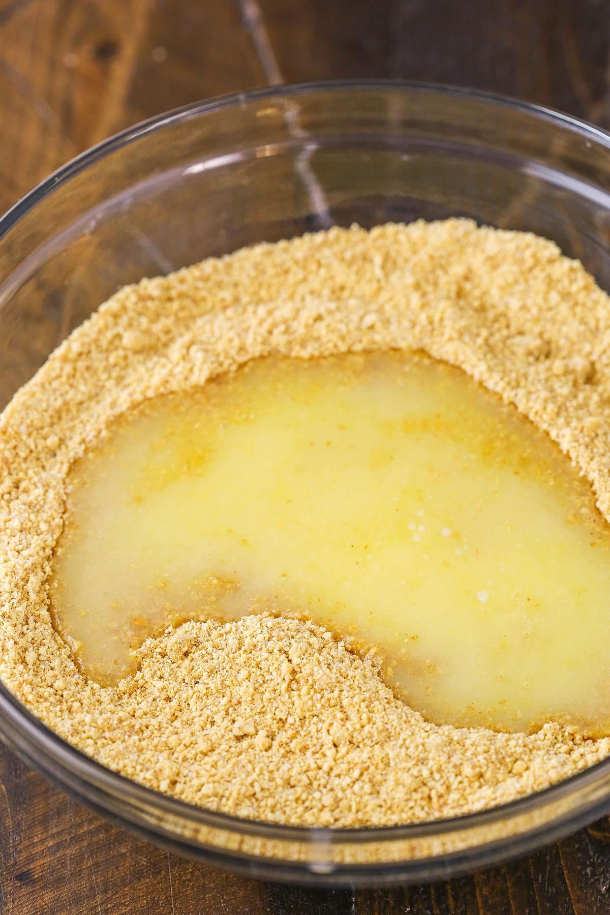 Easy Graham Cracker Crust in a clear glass bowl on a wooden table