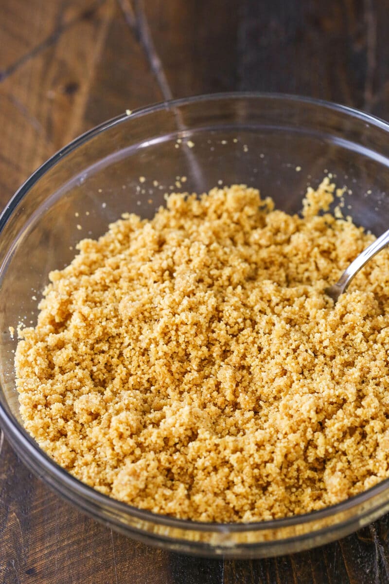 Stirring wet graham cracker crumbs in a glass bowl