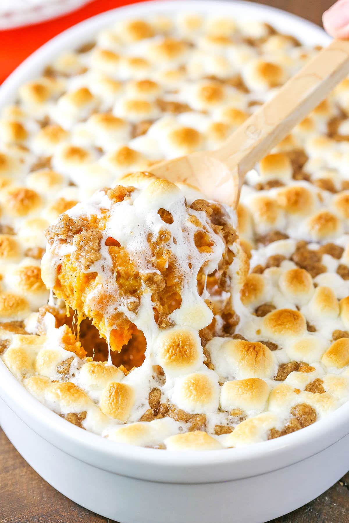 A scoop of Loaded Sweet Potatoes being taken with a wooden spoon