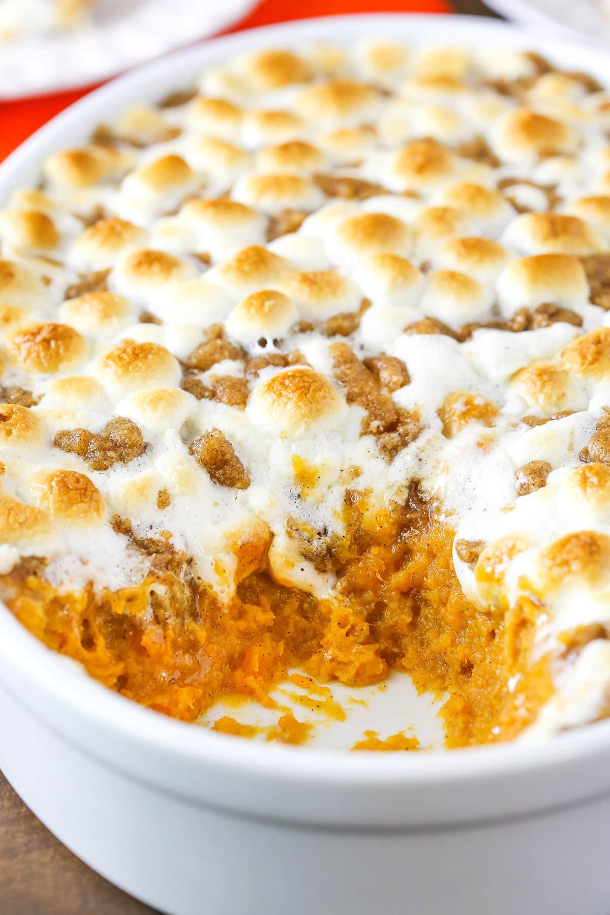 Loaded Sweet Potatoes with a serving removed in a white oval casserole dish on a wooden table