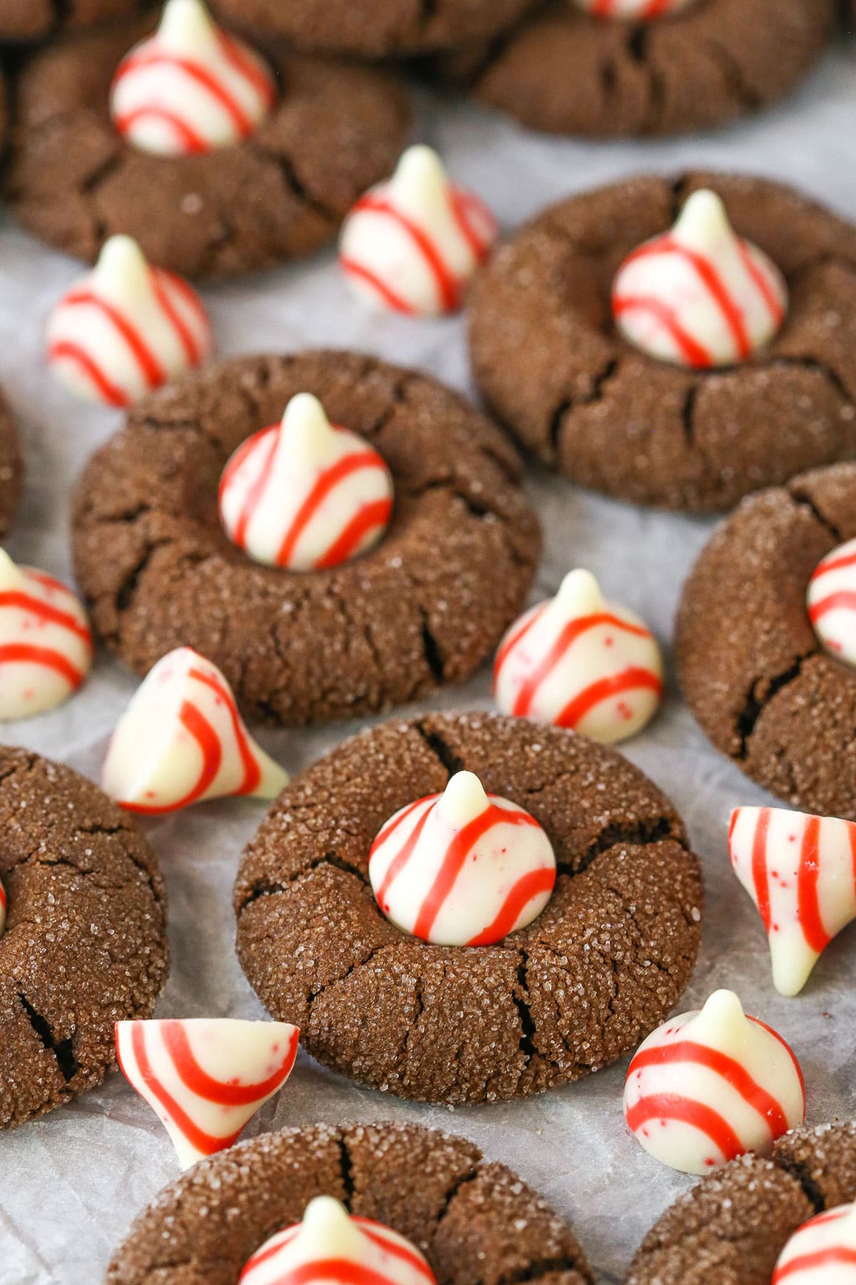 These Peppermint Chocolate Thumbprint Cookies are soft, chewy Christmas chocolate cookies topped with peppermint Hershey kisses - one of my favorite little holiday candies! They are delicious and will make you the hit of your holiday cookie exchange! Peppermint Chocolate Thumbprint Cookies spread evenly over parchment paper