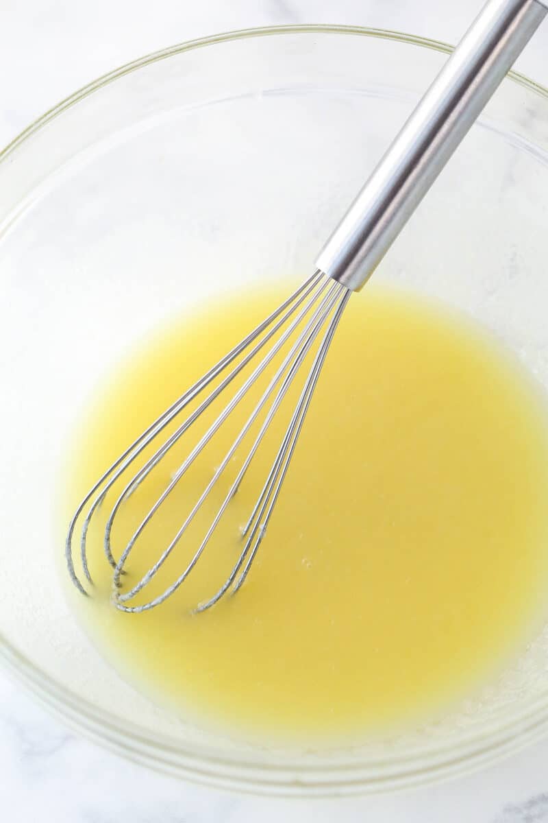 Whisking together melted butter, sugar, and vanilla.