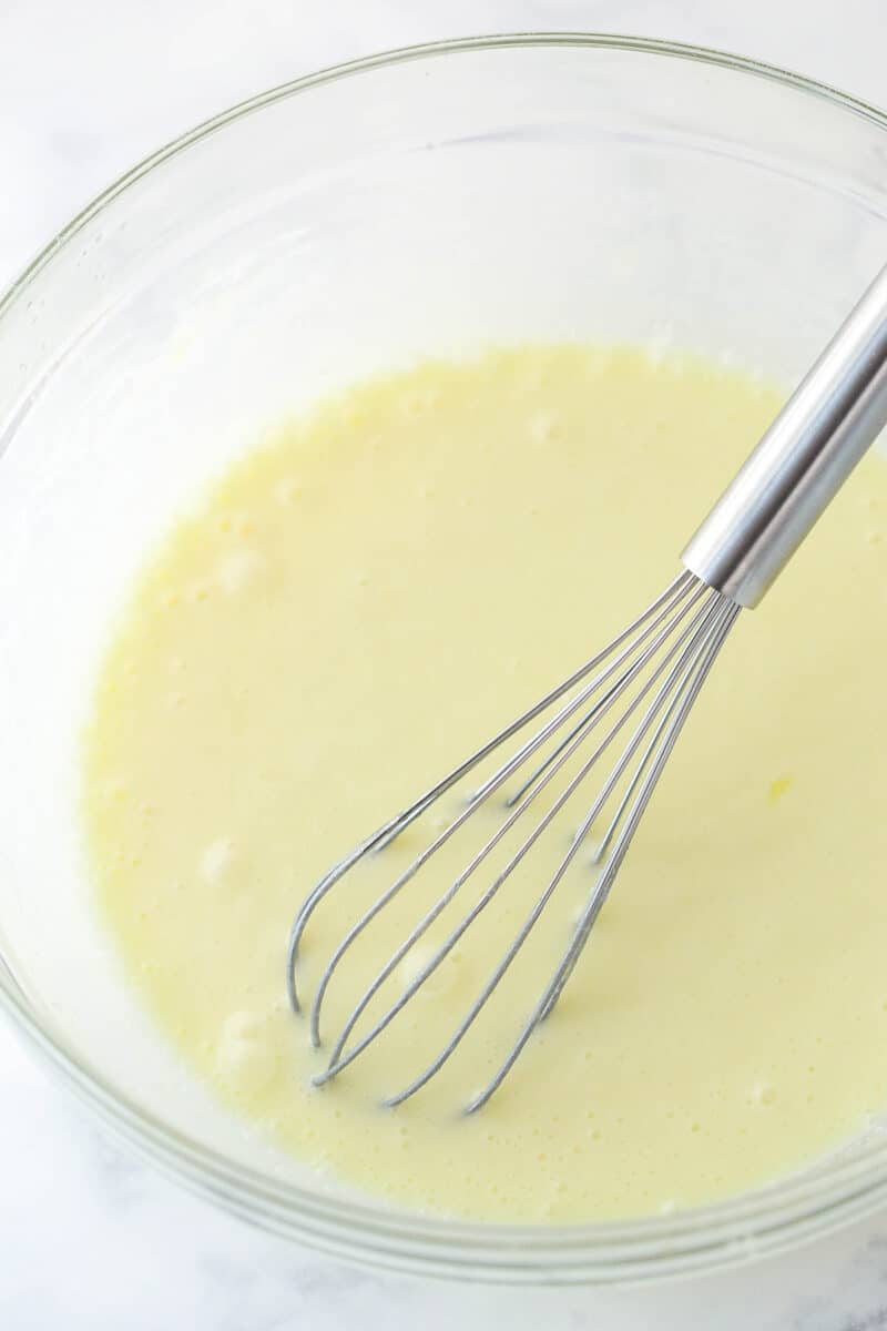 Whisking eggs, sour cream, and milk into cupcake batter.