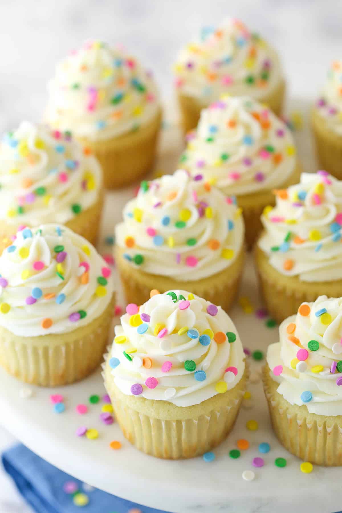 Overhead image of vanilla cupcakes with rainbow dots.