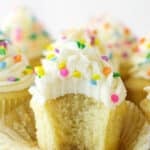 A vanilla cupcake with a bite taken out of it.