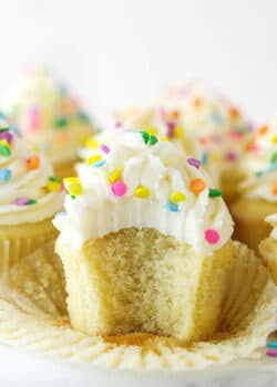 A vanilla cupcake with a bite taken out of it.