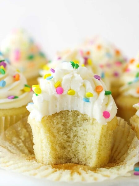 A vanilla cupcake with a bite taken out of it.