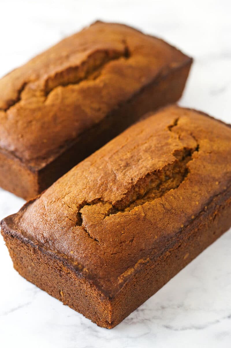 2 loaves of pumpkin bread on a marble counter.