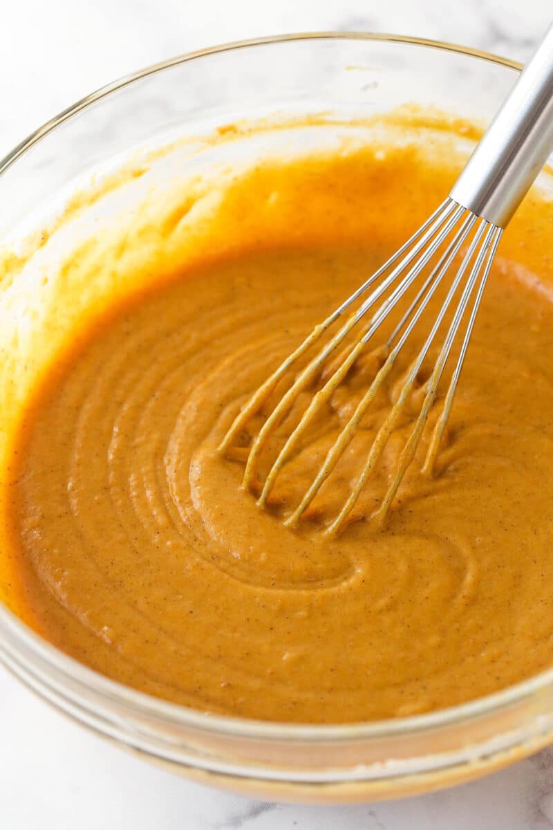 Whisking pumpkin cupcake batter in a mixing bowl.