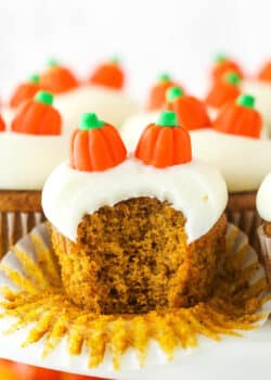 A pumpkin cupcake with a bite taken out of it.