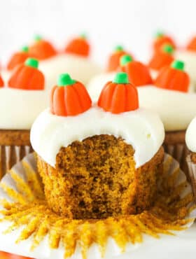 A pumpkin cupcake with a bite taken out of it.