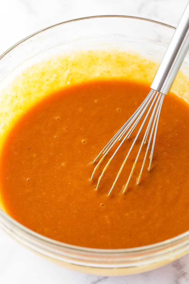 Whisking together wet ingredients for pumpkin cake.