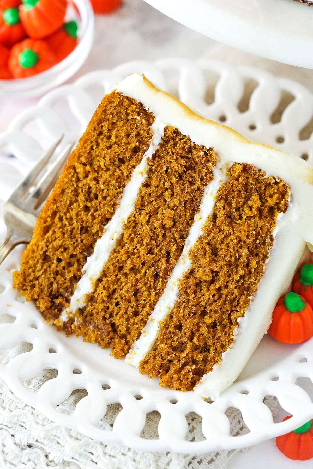 This soft, moist pumpkin layer cake is loaded with warm spices and filled and frosted with a rich, velvety cream cheese frosting. A slice of pumpkin layer cake on a plate.