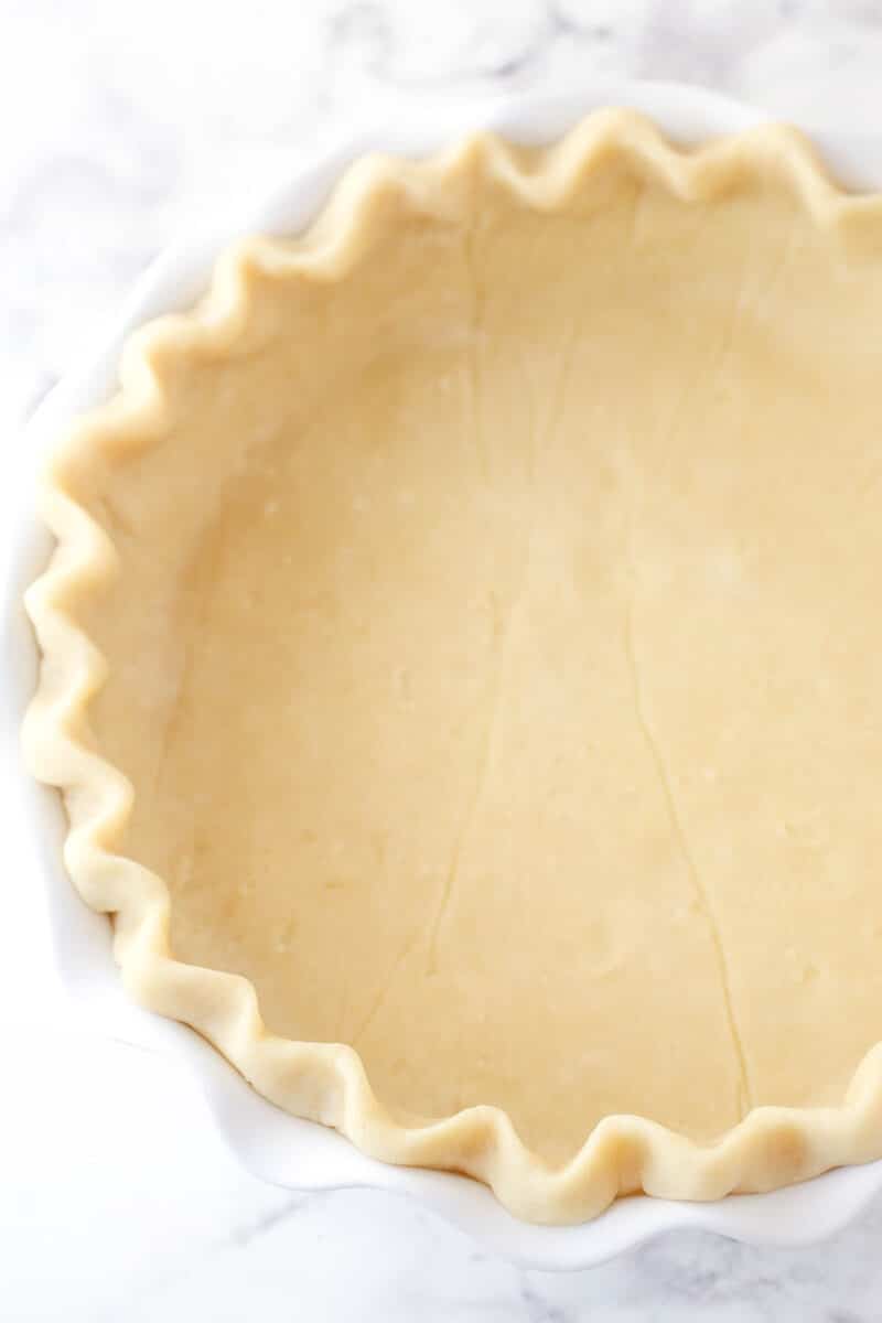 Putting a pie crust in a pie dish and crimping the edges.
