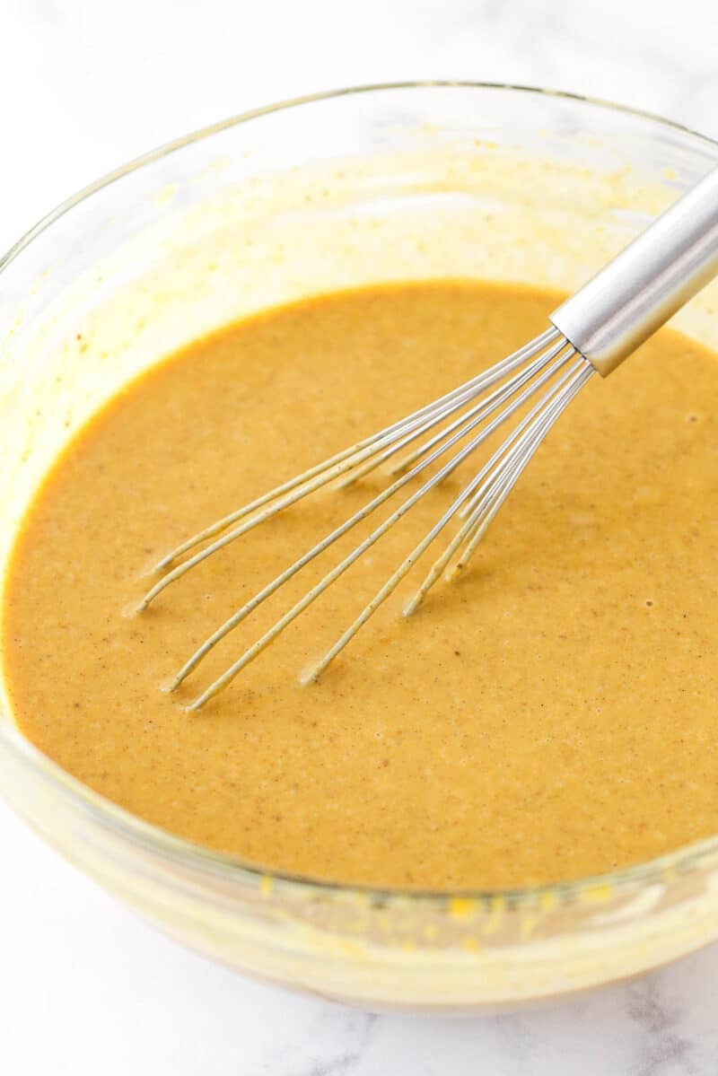 Whisking spices, salt, cornstarch, heavy cream, and milk into pumpkin pie filling.