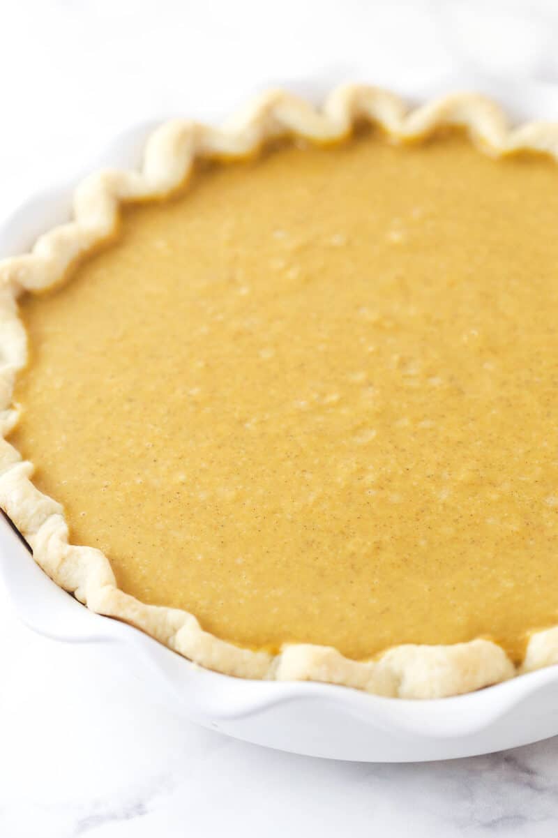 Filling pie crust with pumpkin pie filling.